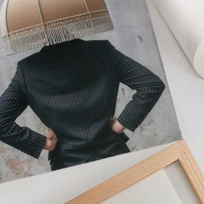 Dekoratyvinis plakatas rafinuoto šviestuvo gaubto ir elegantiško kostiumo tekstūrų kontrastas