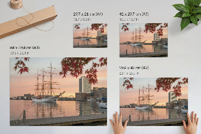 Plakatas ant drobės Burlaivis saulėlydyje, rami miesto panorama