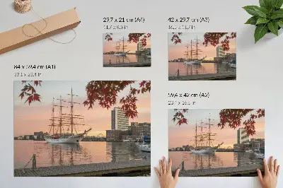 Plakatas ant drobės burlaivis saulėlydyje su ramia miesto panorama