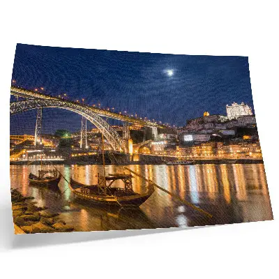 Plakatas tiltas naktį su šviečiančiu miestu ir valtimis vandenyje